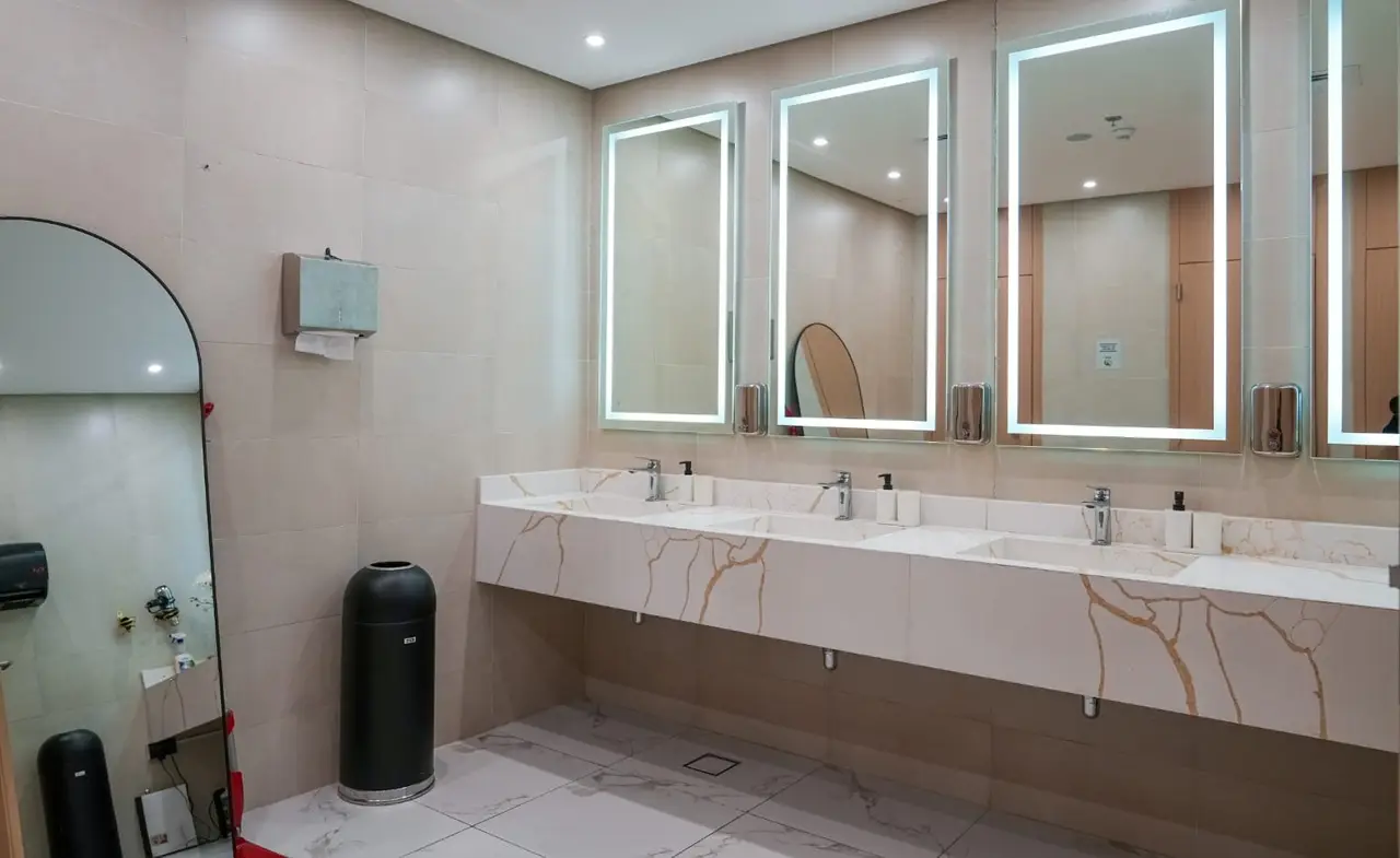 Row of washbasins under lit mirrors at RPM Gym